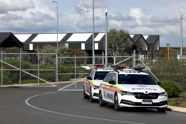 Police cars are parked outside the main gate of the purpose-built quarantine facility located on the outskirts of the Western Australian city of Perth on May 15, 2026, where passengers caught up in the MV Hondius hantavirus outbreak are being quarantined. A plane carrying six passengers caught up in the hantavirus outbreak on the MV Hondius cruise ship landed May 15 at a military airbase in western Australia, where they will immediately enter a strict three-week quarantine. (Photo by Antony DICKSON / AFP)