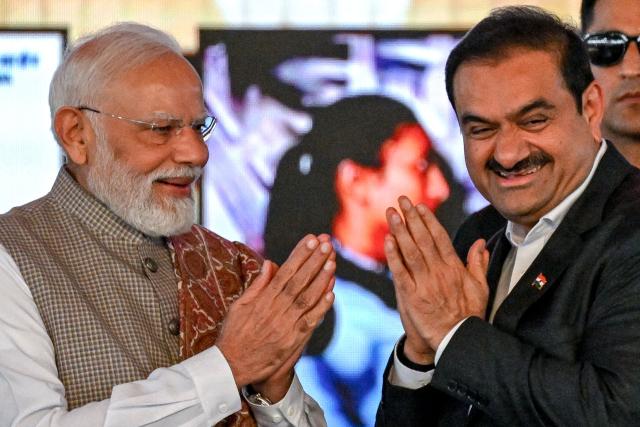 (FILES) India's Prime Minister Narendra Modi (L) greets Gautam Adani, Chairperson of Indian conglomerate Adani Group, during the inauguration ceremony of phase one of the Navi Mumbai International Airport in Navi Mumbai on October 8, 2025. Indian billionaire industrialist Gautam Adani has agreed to pay a multi-million-dollar settlement in a US civil court case linked to corruption without admitting guilt, his company said on May 15, 2026. (Photo by Punit PARANJPE / AFP)