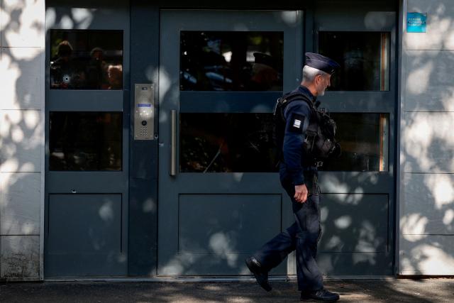 A police officer walks past the front door of a building with bullet holes that was the scene of a shooting in Nantes, western France, on May 15, 2026, where a 15-year-old was killed and two minors were injured. A teenager of about fifteen was shot and killed on the evening of May 14, and two other minors were wounded in a working-class neighborhood of Nantes, which had already been hit by deadly shootings linked to drug trafficking at the end of April. The shooting occurred around 7:30 p.m. in an apartment building, and the suspected shooters, who arrived on a motorcycle, fled the scene, according to multiple sources close to the investigation. The deceased teenager was shot in the heart, these sources confirmed. The two wounded teenagers, who were taken to the hospital, are not in life-threatening condition, according to a source close to the investigation. They are reportedly 13 and 14 years old. (Photo by FRED TANNEAU / AFP)