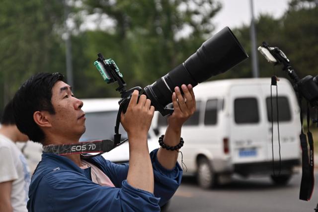 A plane spotter records as Air Force One, carrying US President Donald Trump, takes off from Beijing Capital Airport in Beijing on May 15, 2026. Trump said he had made "fantastic trade deals" with China's Xi Jinping, as the pair met on May 15 at final talks of a superpower summit that according to the US leader has also reaped a Chinese offer to help open the Strait of Hormuz. (Photo by Pedro Pardo / AFP)