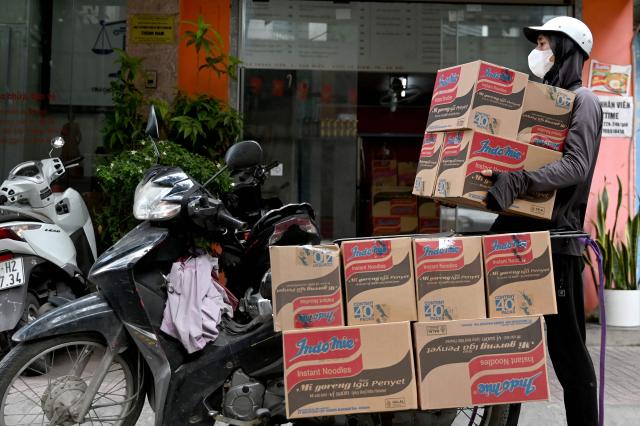 A man carries boxes of instant noodles into a noodle shop in Hanoi on May 15, 2026. (Photo by Nhac NGUYEN / AFP)