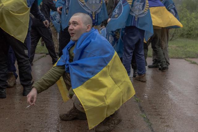 A released Ukrainian prisoner of war (POW) wrapped with Ukrainian national flag smokes following a prisoner exchange at an undisclosed location, in the Chernihiv region on May 15, 2026, amid the Russian invasion of Ukraine. Russia and Ukraine exchanged 205 prisoners of war each on Friday, Moscow and Kyiv said, a week after US President Donald Trump announced a large swap would take place between the warring sides. (Photo by Roman PILIPEY / AFP)