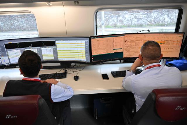 Technicians work on screens aboard a diagnostic train named Diamante 2.0 which reaches a speed of 300 km/h and inspects high-speed lines, during a trip between Rome and Naples, on May 15, 2026. Diamante 2.0 is a train in the Rete Ferroviaria Italiana (RFI) fleet; the special train uses 98 cameras and over 200 sensors placed on the roof and on the trolleys near the wheels to monitor over 500 parameters to collect data on the infrastructure, useful for promptly eliminating possible causes of anomalies and for supporting the scheduling and planning of maintenance operations to be carried out. (Photo by Alberto PIZZOLI / AFP)