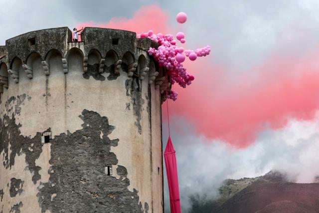 A supporter stands on a decorated tower with pink balloons and pink smoke flares for the passage of the Giro during the 7th stage of the Giro d'Italia 2026 - Tour of Italy cycling race between Formia and Blockhaus, Italy, on May 15, 2026. (Photo by Luca Bettini / AFP)
