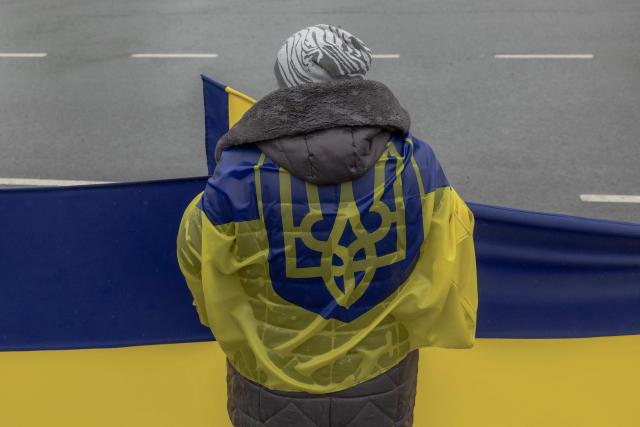 A woman waits along a road to greet released Ukrainian prisoners of war (POWs) following a prisoner exchange, in the Chernihiv region on May 15, 2026, amid the Russian invasion of Ukraine. Russia and Ukraine exchanged 205 prisoners of war each on May 15, Moscow and Kyiv said, a week after US President Donald Trump announced a large swap would take place between the warring sides. (Photo by Roman PILIPEY / AFP)