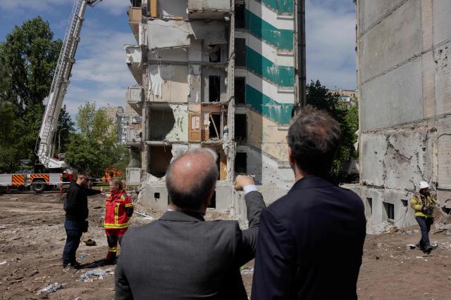 Members of diplomatic missions to Ukraine are standing near a residential building that was partially destroyed following Russian drones and missiles strikes in Kyiv on May 15, 2026, amid the Russian invasion in Ukraine. Ukraine's capital Kyiv was in mourning on May 15, 2026, after a Russian attack killed 24 people a day earlier, with President Volodymyr Zelensky denouncing Moscow's "brutal terror" as the two sides went ahead with an exchange of hundreds of captured soldiers. (Photo by Tetiana DZHAFAROVA / AFP)