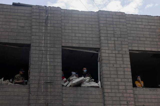 Local residents look out through the broken windows of a damaged residential building following Russian drones and missiles strikes in Kyiv on May 15, 2026, amid the Russian invasion in Ukraine. Ukraine's capital Kyiv was in mourning on May 15, 2026, after a Russian attack killed 24 people a day earlier, with President Volodymyr Zelensky denouncing Moscow's "brutal terror" as the two sides went ahead with an exchange of hundreds of captured soldiers. (Photo by Tetiana DZHAFAROVA / AFP)