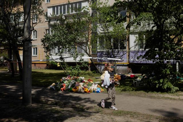 A girl is carrying flowers at a makeshift memorial near a partially destroyed residential building in Kyiv on May 15, 2026, amid the Russian invasion of Ukraine. Ukraine's capital Kyiv was in mourning on May 15, 2026, after a Russian attack killed 24 people a day earlier, with President Volodymyr Zelensky denouncing Moscow's "brutal terror" as the two sides went ahead with an exchange of hundreds of captured soldiers. (Photo by Tetiana DZHAFAROVA / AFP)