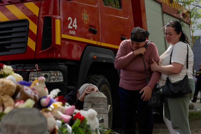 People are crying at a makeshift memorial near a partially destroyed residential building in Kyiv on May 15, 2026, amid the Russian invasion of Ukraine. Ukraine's capital Kyiv was in mourning on May 15, 2026, after a Russian attack killed 24 people a day earlier, with President Volodymyr Zelensky denouncing Moscow's "brutal terror" as the two sides went ahead with an exchange of hundreds of captured soldiers. (Photo by Tetiana DZHAFAROVA / AFP)