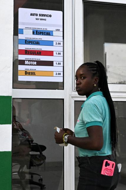 A worker updates a list of fuel prices in US dollars at a petrol station, in Havana, on May 15, 2026. From May 15, Cuba is implementing variable pricing for fuel sold in foreign currency, a measure aimed at addressing rising import costs. Prices at service stations may now fluctuate based on factors such as suppliers, freight, supply routes, insurance and global market volatility, meaning different prices may coexist across the country depending on operational costs. (Photo by YAMIL LAGE / AFP)