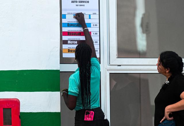 A worker updates a list of fuel prices in US dollars at a petrol station, in Havana, on May 15, 2026. From May 15, Cuba is implementing variable pricing for fuel sold in foreign currency, a measure aimed at addressing rising import costs. Prices at service stations may now fluctuate based on factors such as suppliers, freight, supply routes, insurance and global market volatility, meaning different prices may coexist across the country depending on operational costs. (Photo by YAMIL LAGE / AFP)