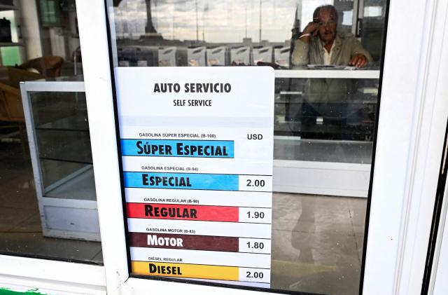 An updated list of fuel prices in US dollars is displayed at a petrol station, in Havana, on May 15, 2026. From May 15, Cuba is implementing variable pricing for fuel sold in foreign currency, a measure aimed at addressing rising import costs. Prices at service stations may now fluctuate based on factors such as suppliers, freight, supply routes, insurance and global market volatility, meaning different prices may coexist across the country depending on operational costs. (Photo by YAMIL LAGE / AFP)
