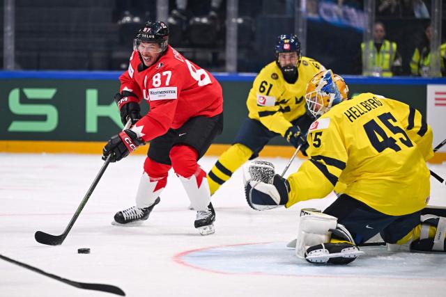 Canada’s forward #87 Sidney Crosby controls the puck next to Sweden's goalkeeper #45 Magnus Hellberg during the group B match between Canada and Sweden at the IIHF Ice Hockey Men's World Championship at BFC Arena, in Fribourg on May 15, 2026. (Photo by Fabrice COFFRINI / AFP)