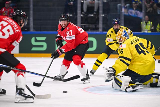 Canada’s forward #87 Sidney Crosby controls the puck next to Sweden's goalkeeper #45 Magnus Hellberg during the group B match between Canada and Sweden at the IIHF Ice Hockey Men's World Championship at BFC Arena, in Fribourg on May 15, 2026. (Photo by Fabrice COFFRINI / AFP)