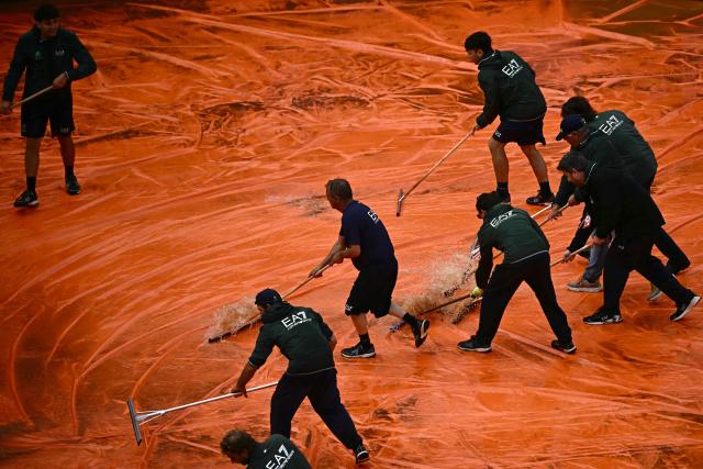 Staff remove water from the tarp covering the clay court after the semi-final match between Italy's Luciano Darderi and Norway's Casper Ruud was interrupted due to a storm during the ATP Rome Open tennis tournament at Foro Italico in Rome on May 15, 2026. (Photo by Filippo MONTEFORTE / AFP)