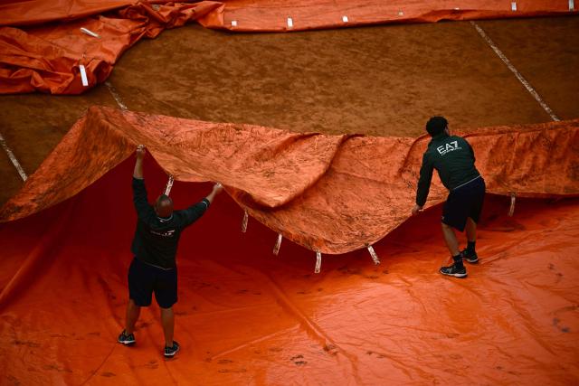 Staff remove the tarp from the clay court after the semi-final match between Italy's Luciano Darderi and Norway's Casper Ruud was interrupted due to a storm during the ATP Rome Open tennis tournament at Foro Italico in Rome on May 15, 2026. (Photo by Filippo MONTEFORTE / AFP)