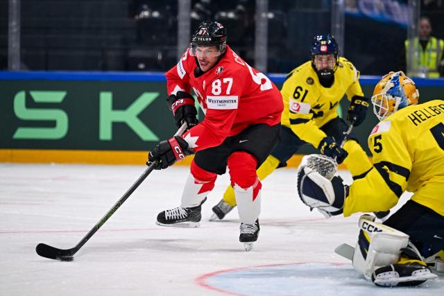 Canada’s forward #87 Sidney Crosby (C) controls the puck next to Sweden's goalkeeper #45 Magnus Hellberg  during the IIHF Ice Hockey Men's World Championship first round group B ice hockey match between Canada and Sweden at the BFC Arena, in Fribourg, Switzerland on May 15, 2026. (Photo by Fabrice COFFRINI / AFP)