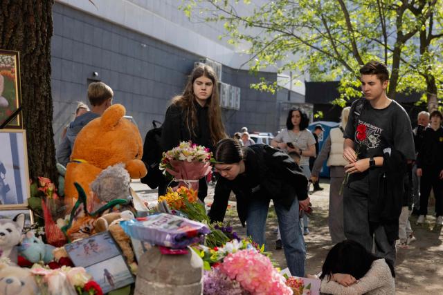 Teenagers are laying flowers at a makeshift memorial near a partially destroyed residential building in Kyiv on May 15, 2026, amid the Russian invasion of Ukraine. Local residents gather at a makeshift memorial near a partially destroyed residential building in Kyiv on May 15, 2026, amid the Russian invasion of Ukraine. (Photo by Tetiana DZHAFAROVA / AFP)