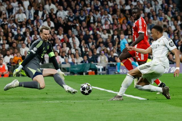 (FILES) Real Madrid's French forward #10 Kylian Mbappe (R) shoots but fails to score past Bayern Munich's German goalkeeper #01 Manuel Neuer during the UEFA Champions League quarter final first leg football match between Real Madrid CF and FC Bayern Munich at Santiago Bernabeu Stadium in Madrid on April 7, 2026. Bayern Munich veteran Manuel Neuer announced on May 15, 2026 that he has extended his contract at the German champions by one year until 2027. The 40-year-old goalkeeper's deal was set to expire in the summer but he will stay on in Munich for what will be a 16th year at the Bavarian giants. (Photo by Oscar DEL POZO / AFP)