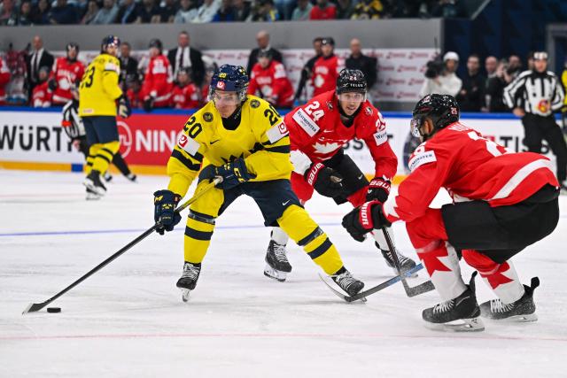 Sweden's forward #20 Andre Petersson (L) controls the puck next to Canada’s forward #24 Dylan Cozens (C) and Canada’s defender #25 Darnell Nurse during the IIHF Ice Hockey Men's World Championship first round group B ice hockey match between Canada and Sweden at the BFC Arena, in Fribourg, Switzerland on May 15, 2026. (Photo by Fabrice COFFRINI / AFP)