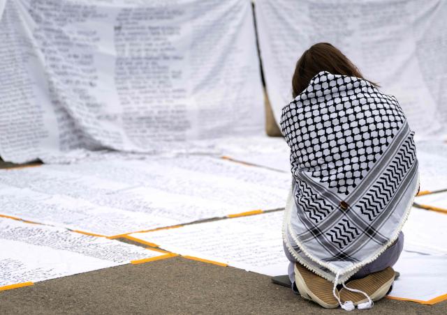 An activists wearing a keffiyeh is seen during an action to write down names of Palestinians, on the sidelines of a pro-Palestinian demonstration under the motto 'Song Protest Vienna 2026 - No Stage for Genocide' against Israel's participation in the Eurovision Song Contest (ESC), in Vienna, Austria, on May 15, 2026. (Photo by Joe Klamar / AFP)