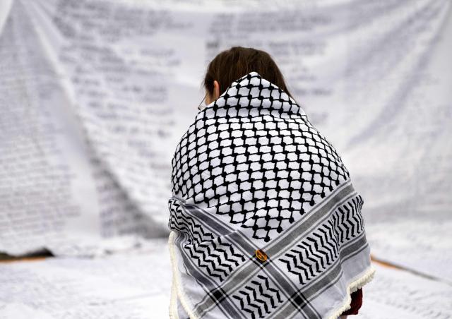 An activist wearing a keffiyeh is seen during an action to write down names of Palestinians, on the sidelines of a pro-Palestinian demonstration under the motto 'Song Protest Vienna 2026 - No Stage for Genocide' against Israel's participation in the Eurovision Song Contest (ESC), in Vienna, Austria, on May 15, 2026. (Photo by Joe Klamar / AFP)