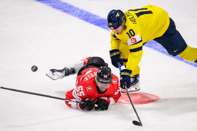 Canada’s forward #55 Mark Scheifele (L) and Sweden's forward #10 Simon Holmstrom fight for the puck during the IIHF Ice Hockey Men's World Championship first round group B ice hockey match between Canada and Sweden at the BFC Arena, in Fribourg, Switzerland on May 15, 2026. (Photo by Fabrice COFFRINI / AFP)