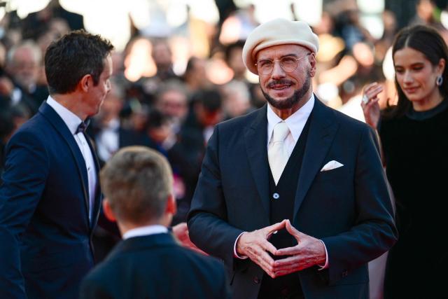 US actress Ella Bleu Travolta and US director, screenwriter and writer John Travolta arrive for the screening of the film "Propeller One-Way Night Coach" at the 79th edition of the Cannes Film Festival in Cannes, southern France on May 15, 2026. (Photo by Olivier CHASSIGNOLE / AFP)