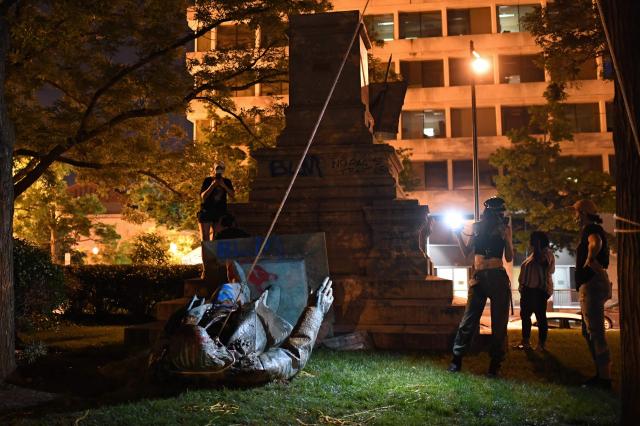 (FILES) People stand around the statue of Confederate general Albert Pike after it was toppled by protesters at Judiciary Square in Wahsington, DC on late June 19, 2020. An executive order from President Donald Trump on "restoring truth and sanity to American history" is changing how history is told at state-owned landmarks as the United States gears up for its 250th independence anniversary in July. The March 2025 order decrees that all monuments and markers within the jurisdiction of the Interior Department -- the parent agency of the park service -- must focus on the "greatness" of US achievements and not "inappropriately disparage Americans past or living." Last October, the only outdoor monument in Washington to honor a Confederate general -- a statue of Albert Pike -- was restored. (Photo by Eric BARADAT / AFP)