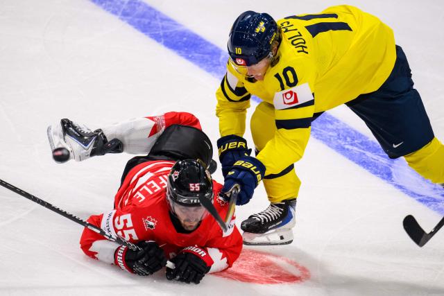 Canada’s forward #55 Mark Scheifele (L) and Sweden's forward #10 Simon Holmstrom fight for the puck during the IIHF Ice Hockey Men's World Championship first round group B ice hockey match between Canada and Sweden at the BFC Arena, in Fribourg, Switzerland on May 15, 2026. (Photo by Fabrice COFFRINI / AFP)