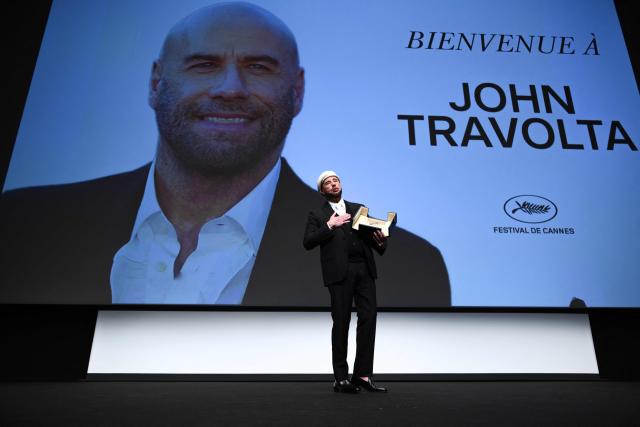 US director, screenwriter and writer John Travolta receives an honourary lifetime achievement Palm d'Or award prior to the screening of the film "Propeller One-Way Night Coach" at the 79th edition of the Cannes Film Festival in Cannes, southern France on May 15, 2026. (Photo by Olivier CHASSIGNOLE / AFP)