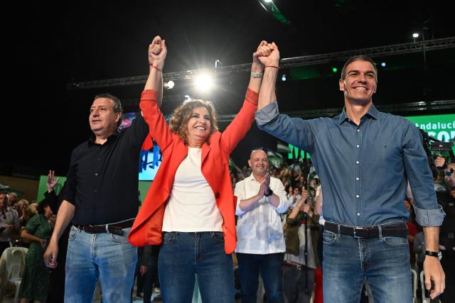 Spain's Prime Minister Pedro Sanchez (R) holds hands with Spanish Socialists Party (PSOE) candidate for the Andalusia's regional government presidency Maria Jesus Montero (C) and PSOE Secretary General of Seville Javier Fernandez de los Rios during the closing campaign rally for Andalusia regional elections in Seville on May 15, 2026. The Socialists of Prime Minister Pedro Sanchez face a key electoral challenge May 16, 2026 in Andalusia, Spain's most populous region, following a string of defeats to the right wing a year before the general election. (Photo by CRISTINA QUICLER / AFP)