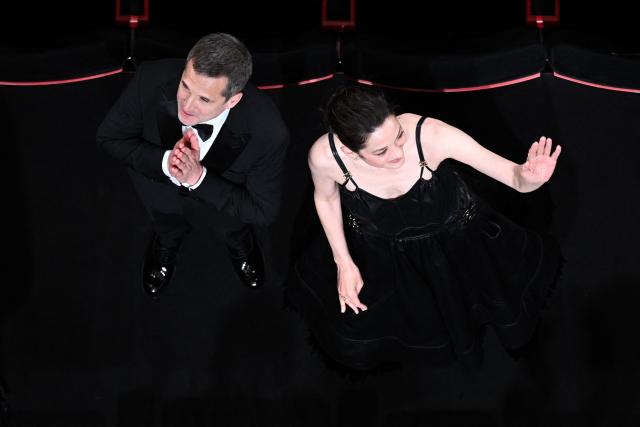 French director and screenwriter Guillaume Canet (L) and French actress Marion Cotillard acknowledge the audiences after the screening of the film "Karma" at the 79th edition of the Cannes Film Festival in Cannes, southern France on May 15, 2026. (Photo by Antonin THUILLIER / AFP)