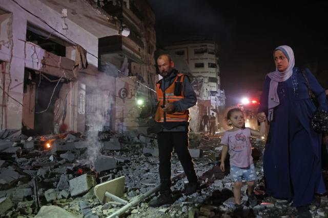 TOPSHOT - A first responder escorts a woman and child through the site of an Israeli strike in the Rimal neighbourhood of Gaza City on May 15, 2026. Israel said on May 15 that it carried out a strike in Gaza targeting Ezzedine Al-Haddad, who it described as chief of the armed wing of Palestinian movement Hamas. Since Hamas's October 7, 2023 attack on Israel, the Israeli military and intelligence services have waged an extensive campaign targeting the group's senior political leaders and militant commanders in Gaza and across the region. (Photo by Omar AL-QATTAA / AFP)