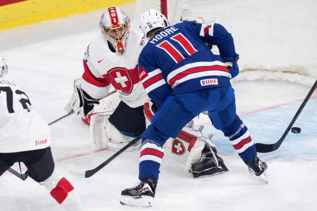 Switzerland's goalkeeper #63 Leonardo Genoni (L) fights for the puck with USA's forward #11 Oliver Moore (R) during the IIHF Ice Hockey Men's World Championship first round group A ice hockey match between USA and Switzerland at the Swiss Life Arena, in Zurich, on May 15, 2026. (Photo by ENNIO LEANZA / AFP)