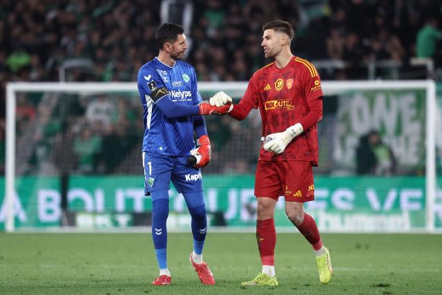 Saint-Etienne's French goalkeeper #01 Brice Maubleu (L) and Rodez's French goalkeeper #01 Quentin Braat (R) touch gloves ahead of the penalty shoot out at end of extra time during the French L1-L2 playoff second leg football match between AS Saint-Etienne and Rodez at the stade Geoffroy Guichard in Saint-Etienne, south-eastern France, on May 15, 2026. (Photo by Alex MARTIN / AFP)