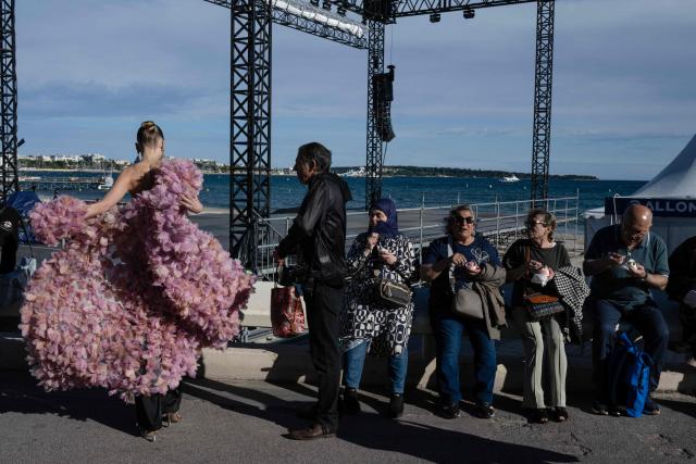 A woman in evening attire walks on the Boulevard de la Croissette ahead of the screening of the film "Karma" at the 79th edition of the Cannes Film Festival in Cannes southern France on May 15, 2026. (Photo by Blanca CRUZ / AFP)