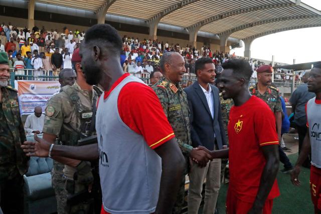 Sudan's de facto leader and army chief Abdel Fattah al-Burhan (C) greets the players after attending the Sudanese Premier League's opening football match between Al Merrikh and Ahli Madani at the Kober Stadium in Khartoum North, on May 15, 2026. Football returned to Sudan's war-scarred capital on May 15 as the domestic league staged its first matches since the conflict began at battered stadiums on the edges of a largely abandoned Khartoum. (Photo by Ebrahim Hamid / AFP)