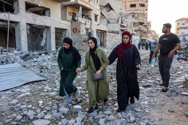 People walk outside a residential building that was hit by an Israeli strike the previous day in the Rimal neighbourhood of Gaza City on May 16, 2026. Israel said on May 15 that it carried out a strike in Gaza targeting Ezzedine Al-Haddad, who described it as chief of the armed wing of Palestinian movement Hamas. Since Hamas's October 7, 2023 attack on Israel, the Israeli military and intelligence services have waged an extensive campaign targeting the group's senior political leaders and militant commanders in Gaza and across the region. (Photo by Omar AL-QATTAA / AFP)