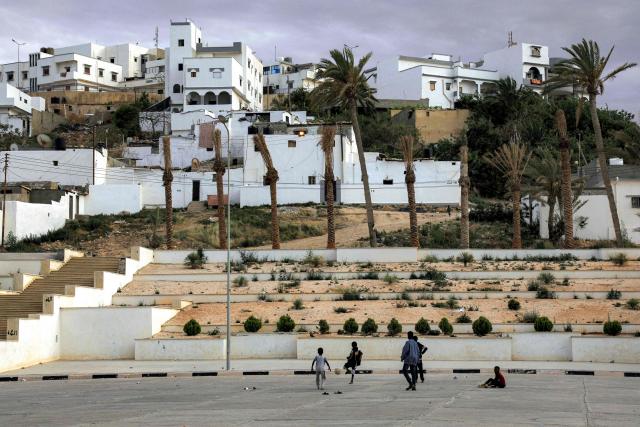 Children play with a ball at a car park near a residential neighbourhood in Libya's eastern city of Derna on May 15, 2026, following reconstruction and reurbanisation efforts over two years after after extreme rainfall from the hurricane-strength Storm Daniel caused two dams to burst and cause flooding, killing thousands and razing entire neighbourhoods in the city. (Photo by Abdullah DOMA / AFP)