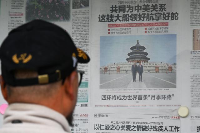 A man reads a newspaper with an article about meetings between China’s President Xi Jinping and US President Donald Trump, with a photo of them visiting the Temple of Heaven, at a newspaper display board in Beijing on May 16, 2026. (Photo by GREG BAKER / AFP)