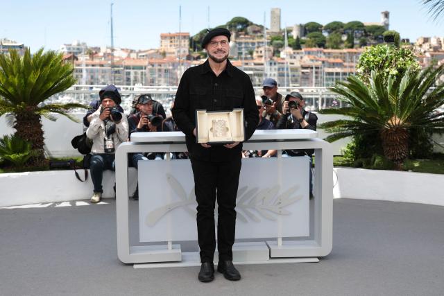 US director, screenwriter and writer John Travolta poses with an honourary lifetime achievement Palm d'Or award during a photocall of the film "Vol de nuit pour Los Angeles" (Propeller One-Way Night Coach) at the 79th edition of the Cannes Film Festival in Cannes, southern France on May 16, 2026. (Photo by Sameer AL-DOUMY / AFP)