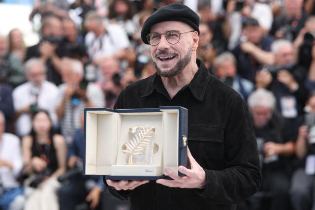 US director, screenwriter and writer John Travolta poses with an honourary lifetime achievement Palm d'Or award during a photocall of the film "Vol de nuit pour Los Angeles" (Propeller One-Way Night Coach) at the 79th edition of the Cannes Film Festival in Cannes, southern France on May 16, 2026. (Photo by Valery HACHE / AFP)