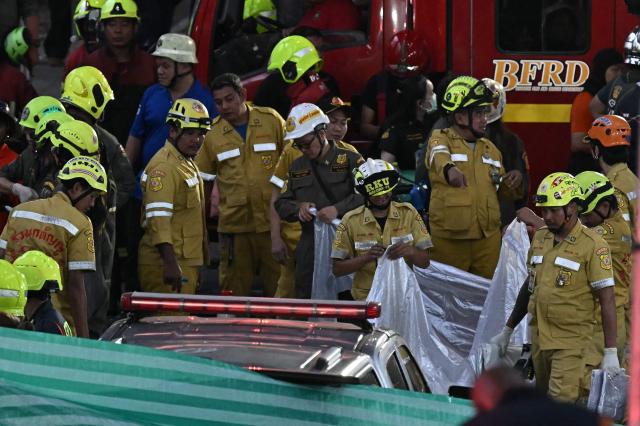 Rescue workers are seen at the site of a train collision with a bus underneath Makkasan Airport Rail station in Bangkok on May 16, 2026. A collision between a freight train and a bus killed at least eight people and injured more than 20 in the Thai capital Bangkok, emergency services said. (Photo by Lillian SUWANRUMPHA / AFP)