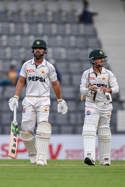 Pakistan's Azan Awais (R) and Abdullah Fazal walk off the field at the end of the the first day of the second Test cricket match between Bangladesh and Pakistan at the Sylhet International Cricket Stadium in Sylhet on May 16, 2026. (Photo by Munir UZ ZAMAN / AFP)