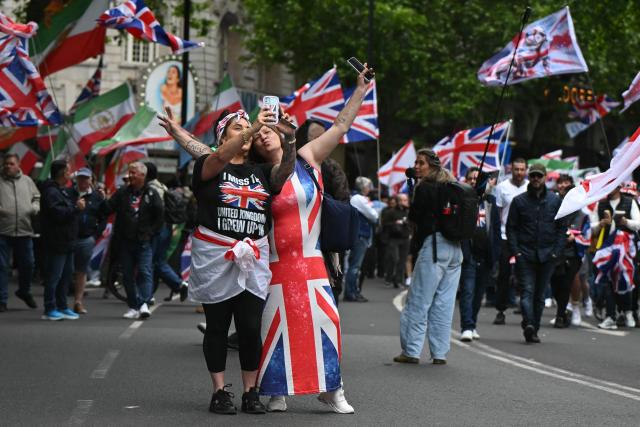 Supporters of British far-right activist Tommy Robinson, real name Stephen Yaxley-Lennon, take a selfie photo as they take part in a march organised by Unite The Kingdom, in central London on May 16, 2026. (Photo by JUSTIN TALLIS / AFP)