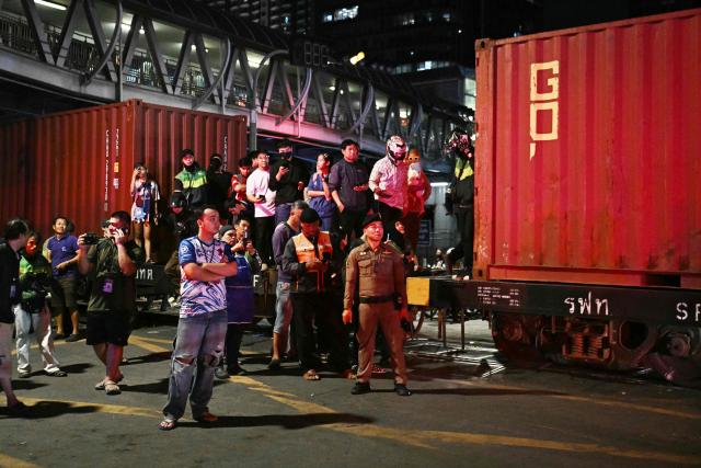 Onlookers stand on a carriage of a train that collided with a bus underneath Makkasan Airport Rail station in Bangkok on May 16, 2026. A collision between a freight train and a bus killed at least eight people and injured more than 30 in the Thai capital Bangkok, emergency services said. (Photo by Lillian SUWANRUMPHA / AFP)