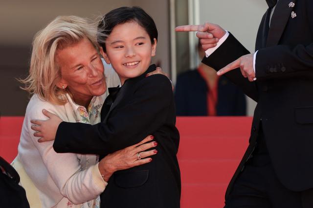 President of the Cannes Film Festival Iris Knobloch (L) greets Japanese actor Rimu Kuwaki as he arrives for the screening of the film "Sheep in The Box" at the 79th edition of the Cannes Film Festival in Cannes, southern France on May 16, 2026. (Photo by Thibaud MORITZ / AFP)