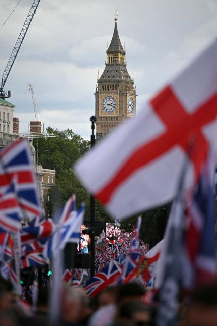 Supporters of British far-right activist Tommy Robinson, real name Stephen Yaxley-Lennon, wave flags as they take part in a march organised by Unite The Kingdom, in central London on May 16, 2026. (Photo by JUSTIN TALLIS / AFP)