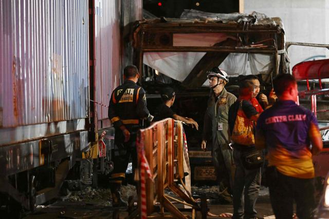 Rescue workers stand at the site of a train collision with a bus underneath Makkasan Airport Rail station in Bangkok on May 16, 2026. A collision between a freight train and a bus killed at least eight people and injured more than 30 in the Thai capital Bangkok, emergency services said. (Photo by Lillian SUWANRUMPHA / AFP)